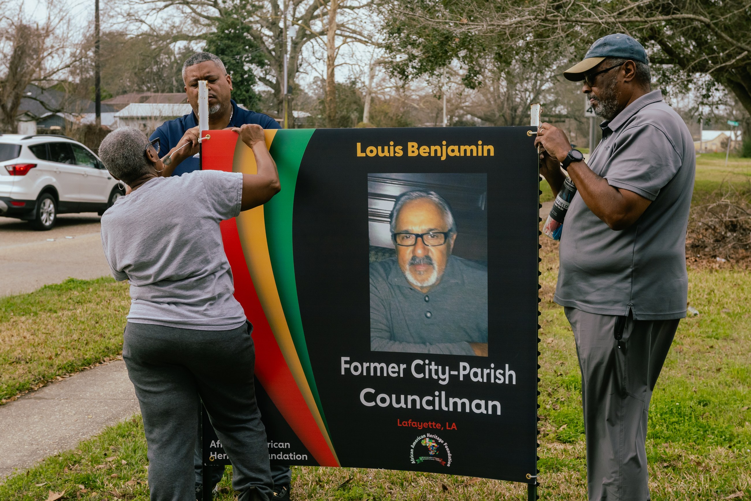 Volunteers hang a Foundation banner honoring former City-Parish Councilman Louis Benjamin