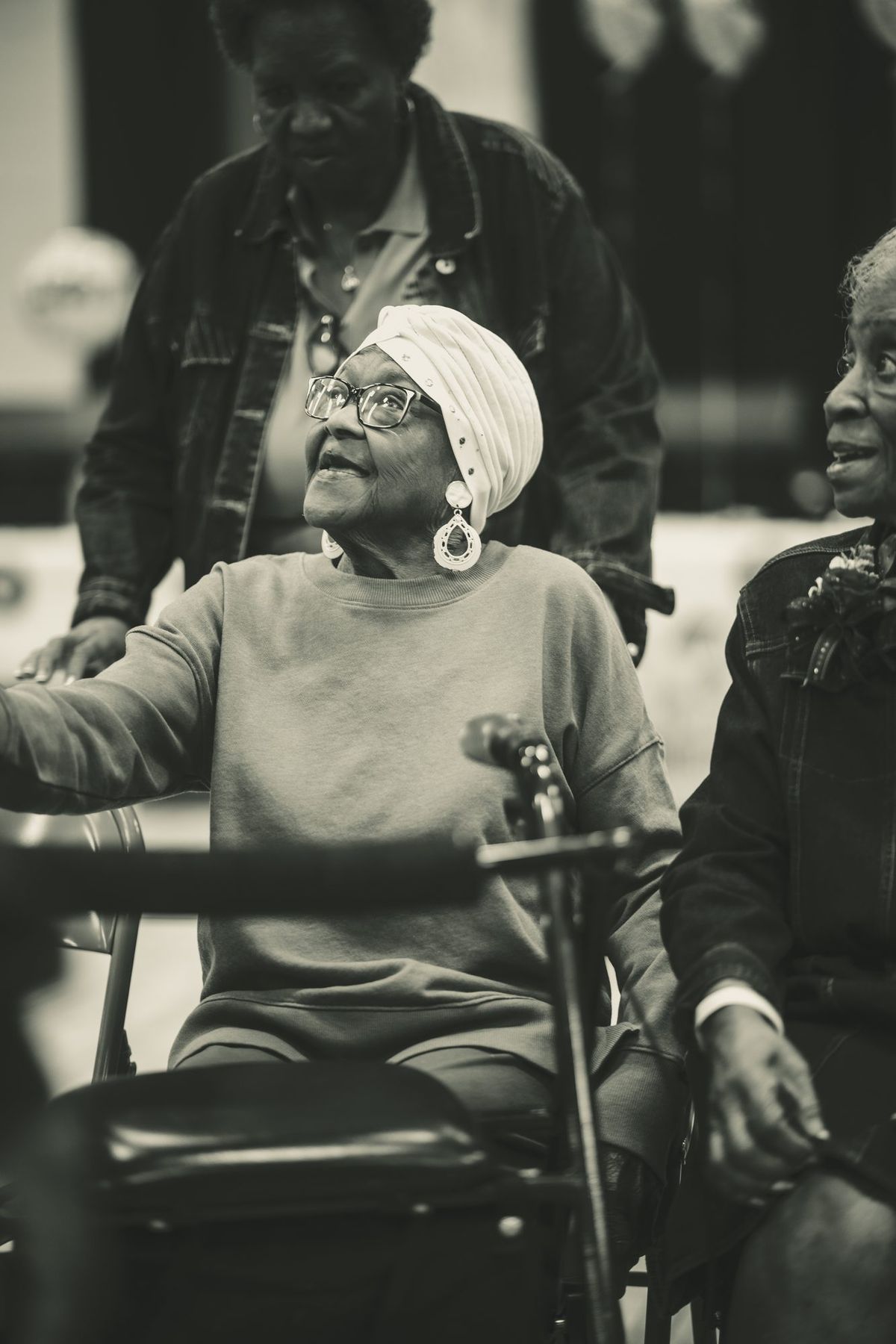 An elder in a head wrap looks up with a smile