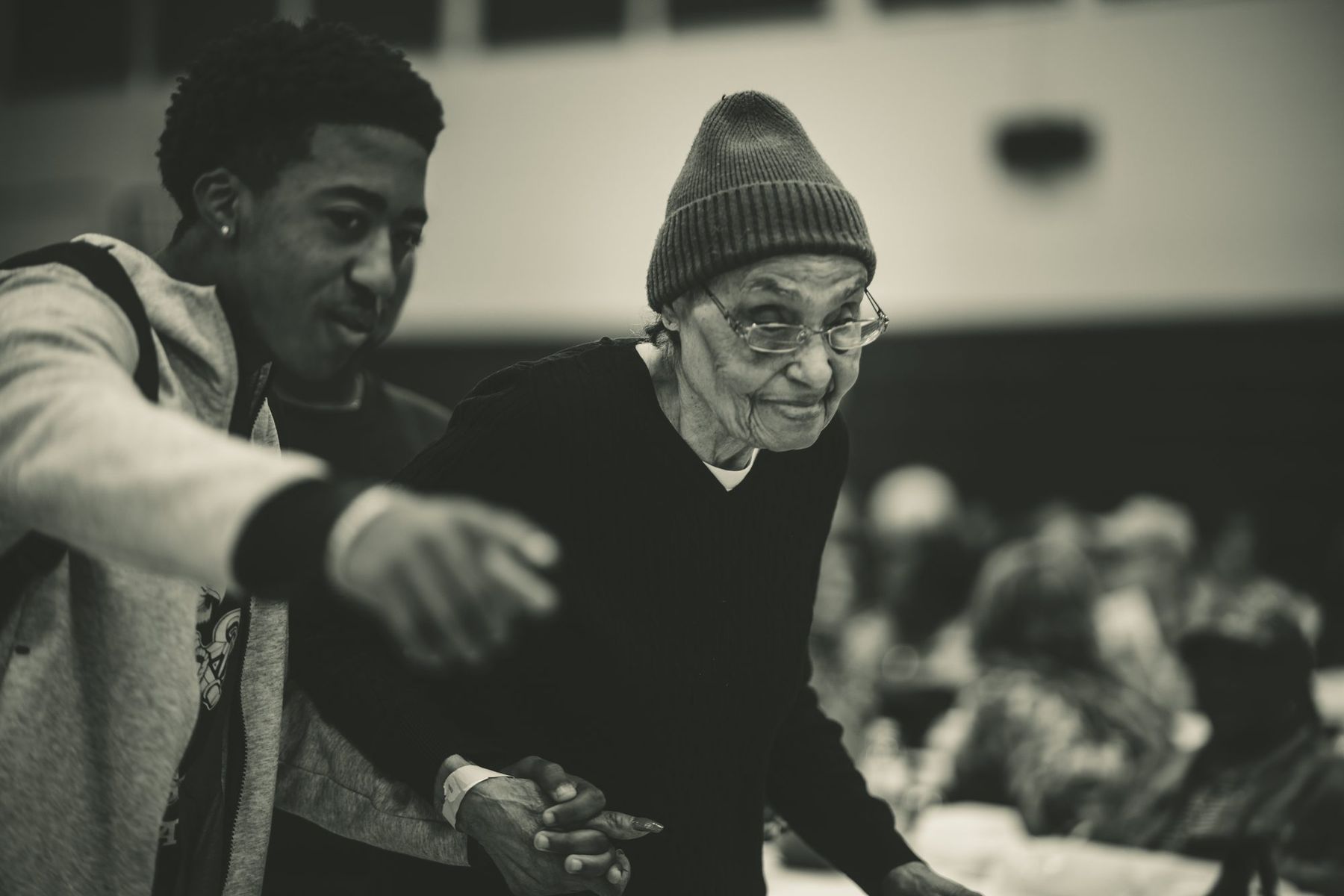 A young man helping an elder across the floor